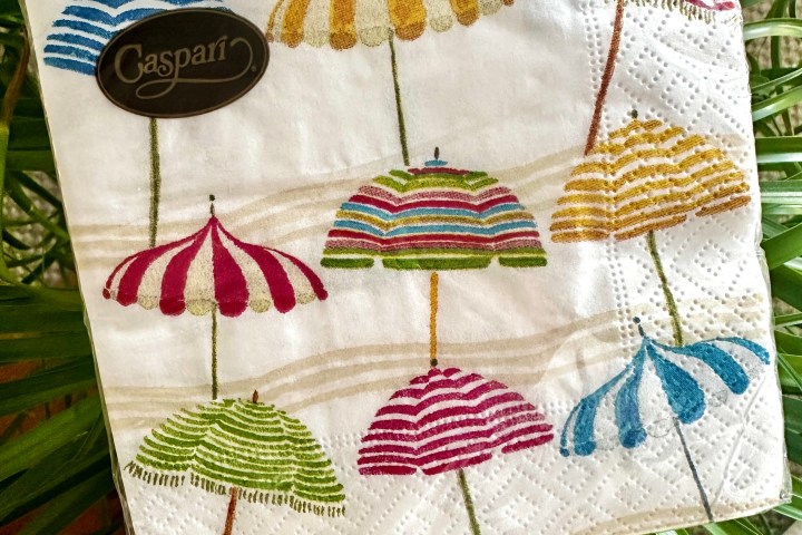 Colorful umbrella pattern on napkins with green leaves in background.