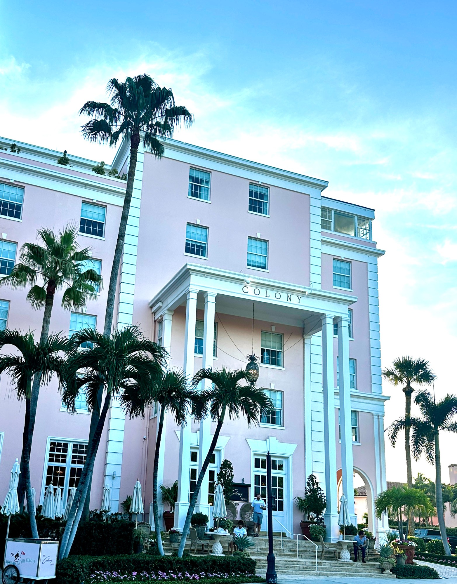 Pink hotel with tall palm trees and a clear blue sky.