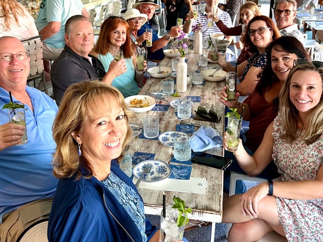 Group of people seated at a restaurant table, raising drinks and smiling.