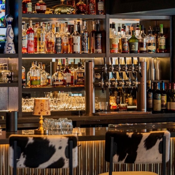 Bar with various liquor bottles, beer taps, and cowhide bar stools.